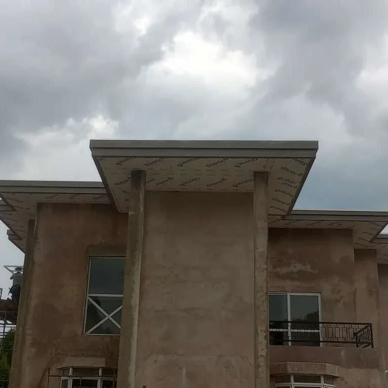 Beiral plano de uma casa de dois pavimentos em reboco, sob céu nublado.